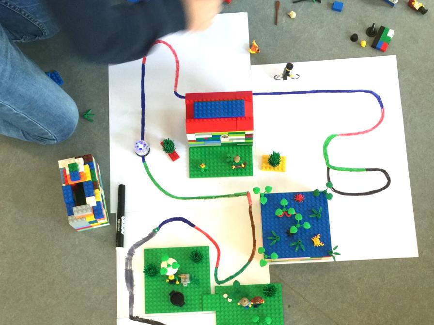 En ozobot der kører på en bane tegnet på papir med forskellige farver. 